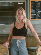 Mulher com top preto e calças cinzas, destacando conforto e estilo casual, usando produto da marca Greenish.