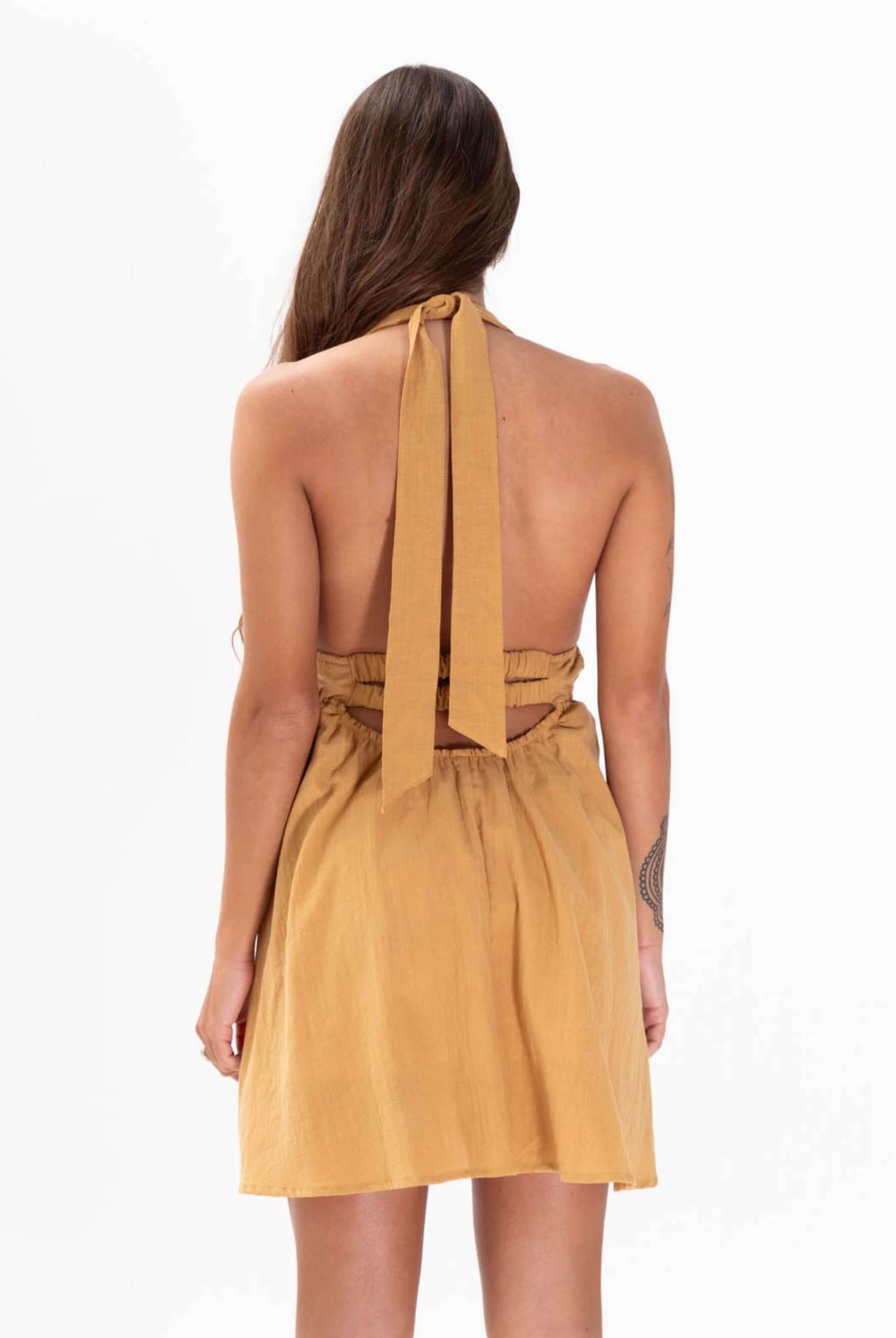 Modelo usando vestido curto Billy bege da Greenish, com detalhes nas costas e laço no pescoço.