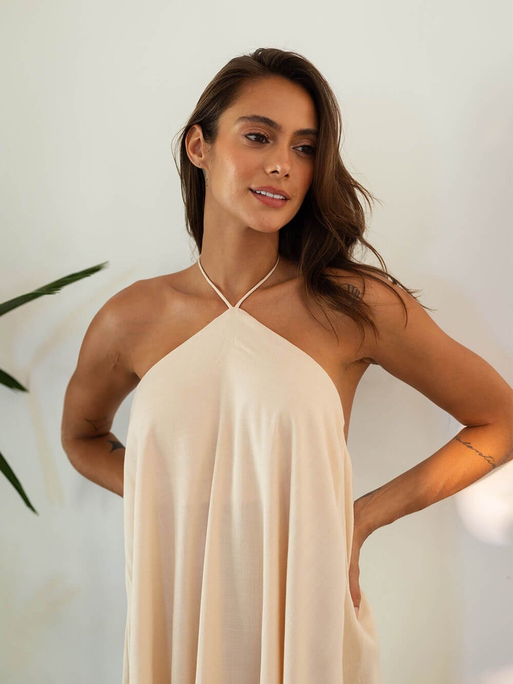 Modelo usando vestido curto Francis bege da Greenish, com amarração no pescoço e design minimalista.