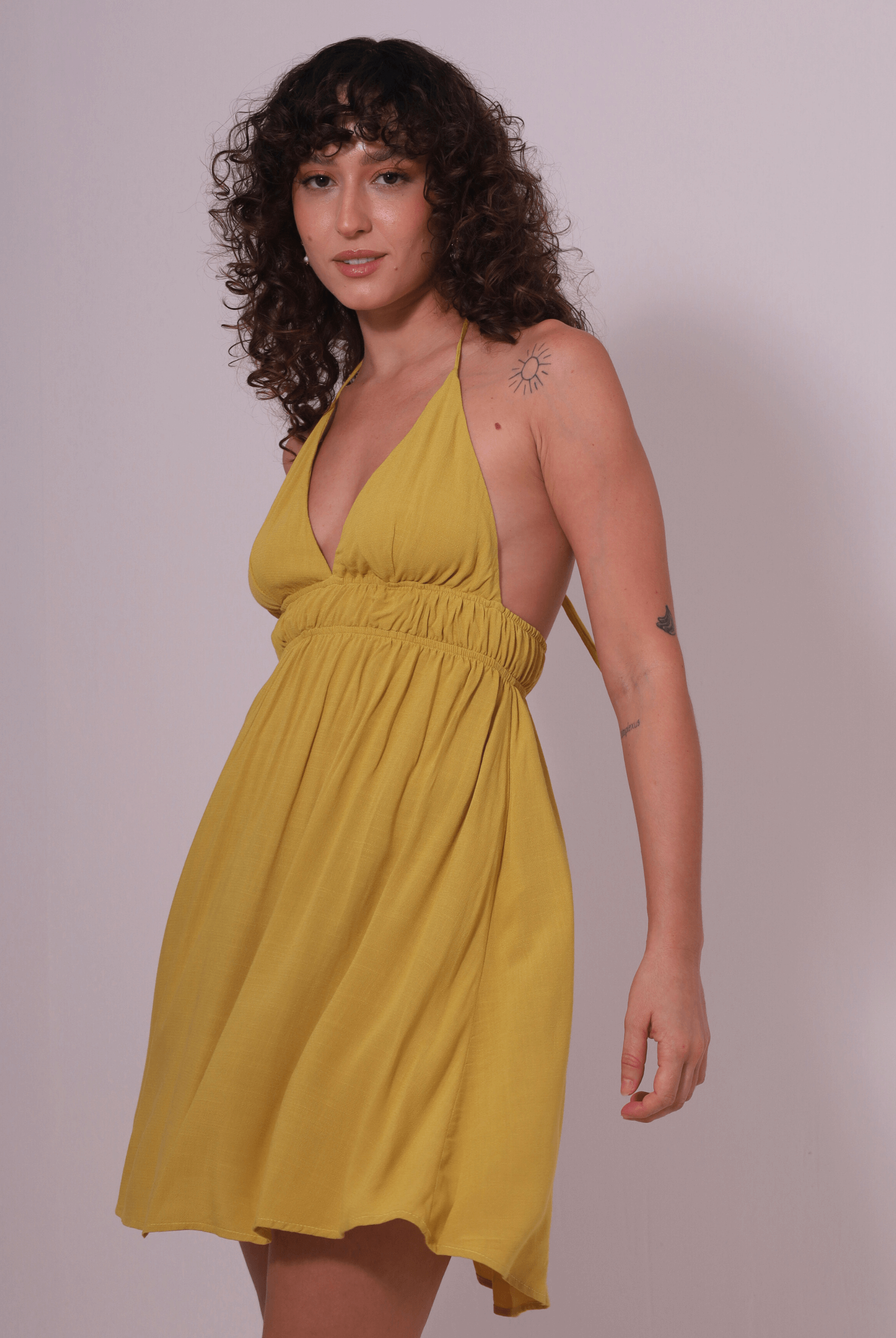 Mulher usando Vestido Curto Lara amarelo pistache da Greenish, feito em malha 100% viscose, ideal para dias descontraídos.