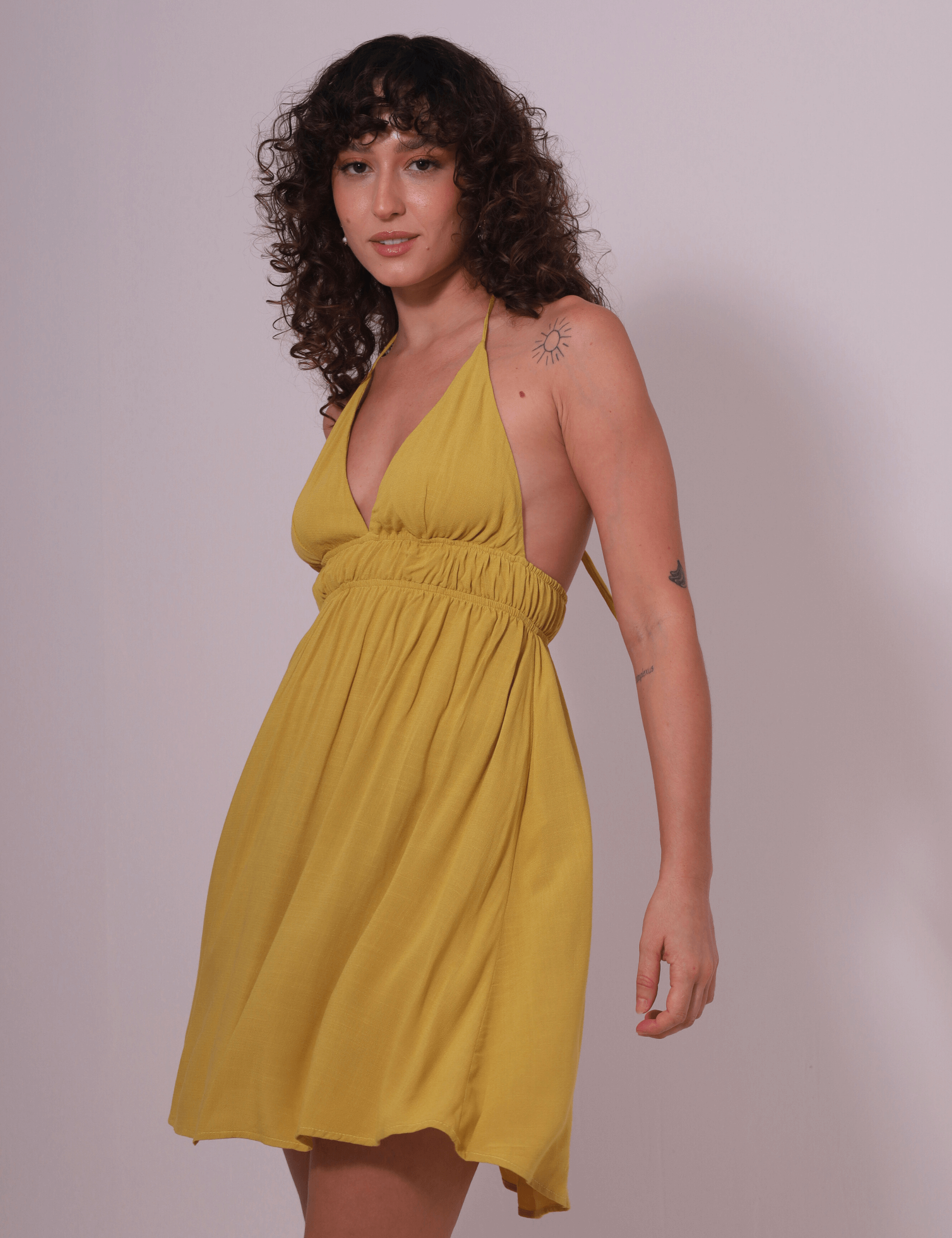 Mulher usando Vestido Curto Lara amarelo pistache da Greenish, feito em malha 100% viscose, ideal para dias descontraídos.