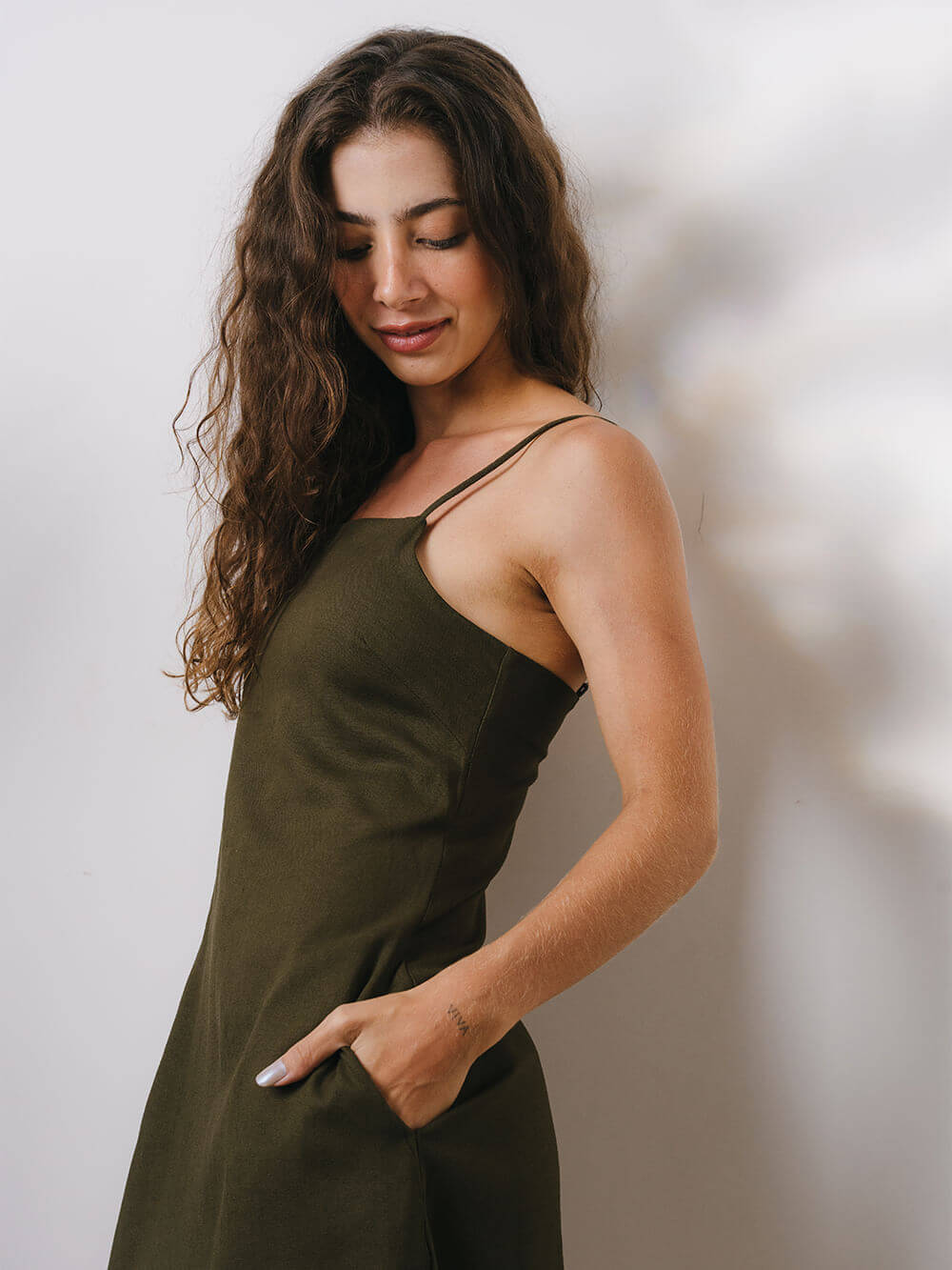 Modelo usando o vestido curto Maggie verde da marca Greenish, com caimento elegante e bolsos laterais.