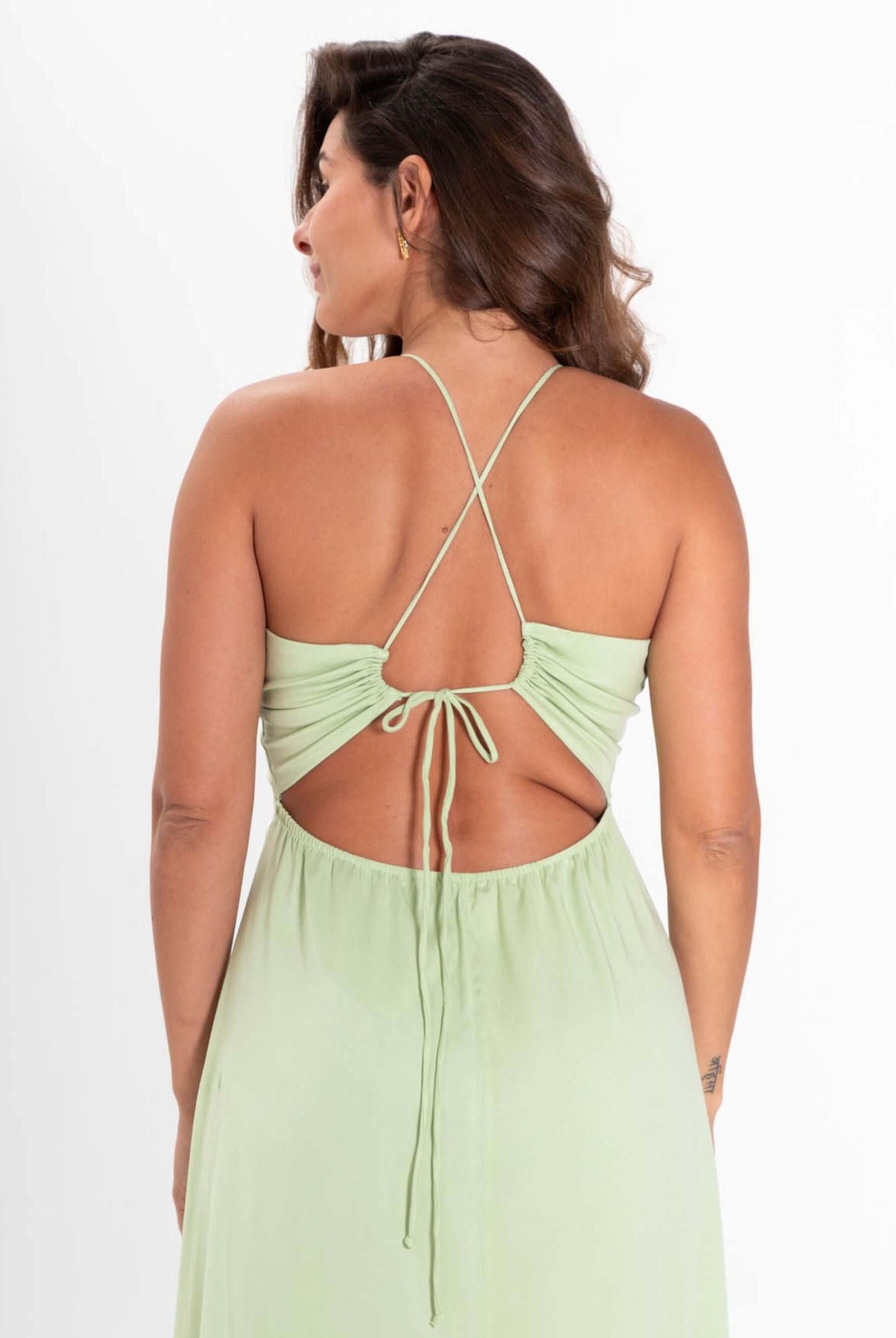 Modelo usando o vestido midi Alex verde claro da Greenish, com detalhes de amarração nas costas.