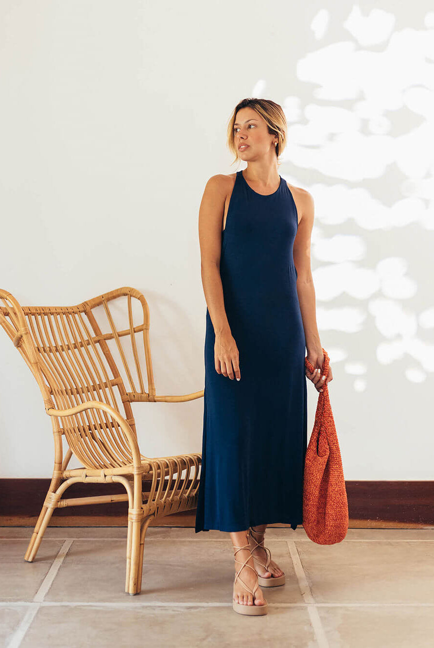 Modelo usando vestido midi Frankie azul marinho da Greenish, estilo sofisticado e moderno, com bolsa vermelha.