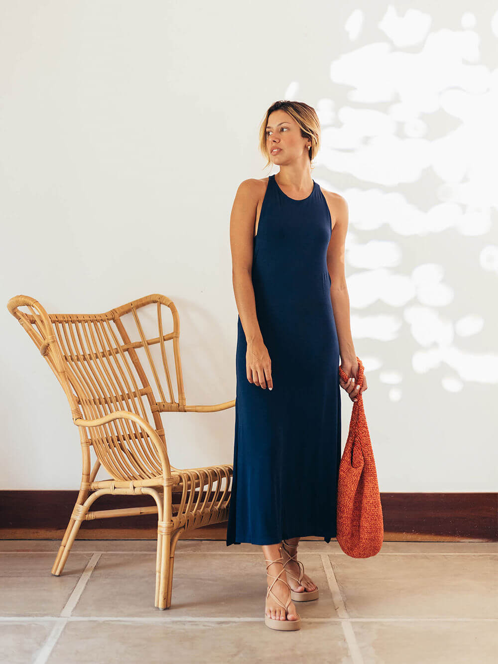 Modelo usando vestido midi Frankie azul marinho da Greenish, estilo sofisticado e moderno, com bolsa vermelha.