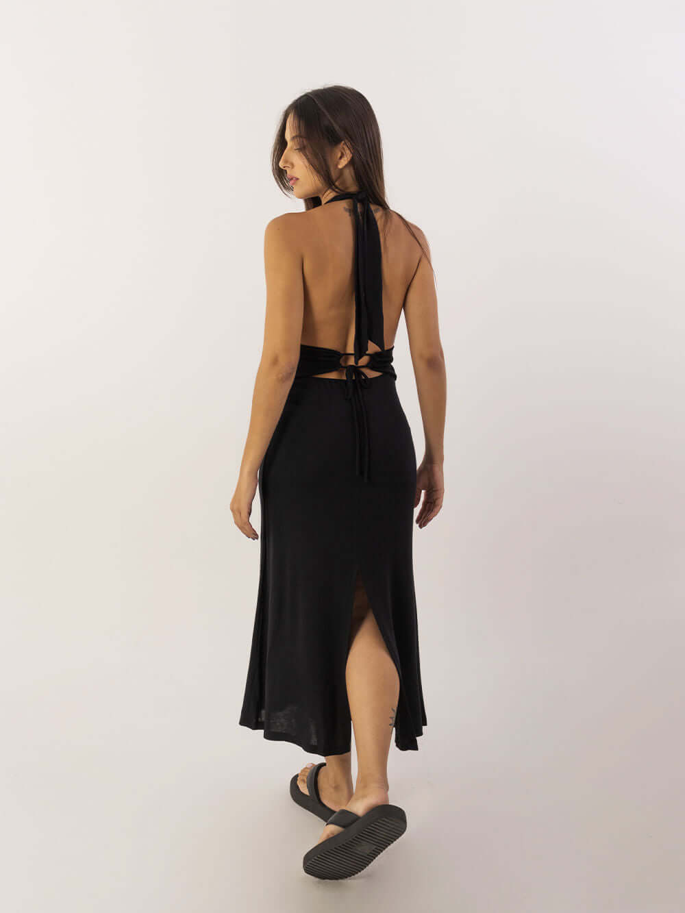 Vestido Midi Mary da Greenish em preto, modelo de costas, com detalhe de amarração e fenda.