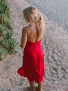Mulher usando vestido midi vermelho da marca Greenish, com decote em V, na praia.