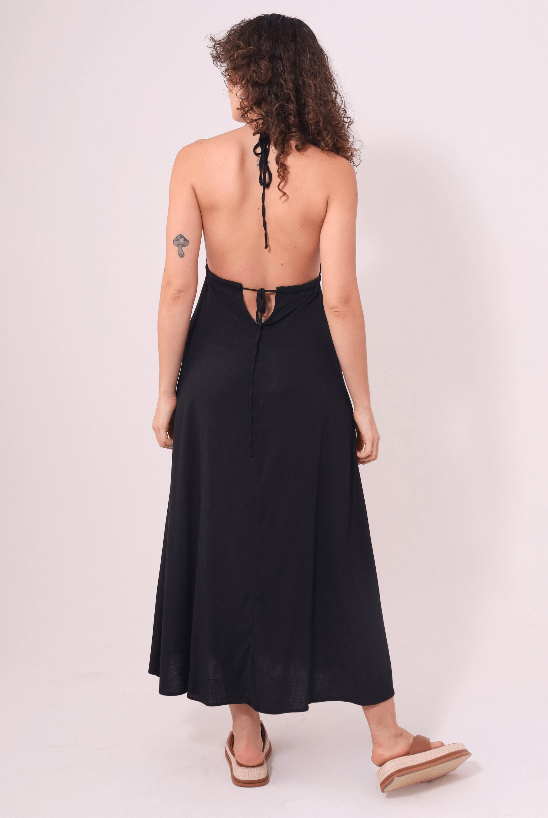 Mulher vestindo o Vestido Midi Tarsila Preto da Greenish com alças finas e costas abertas, destacando elegância e conforto.