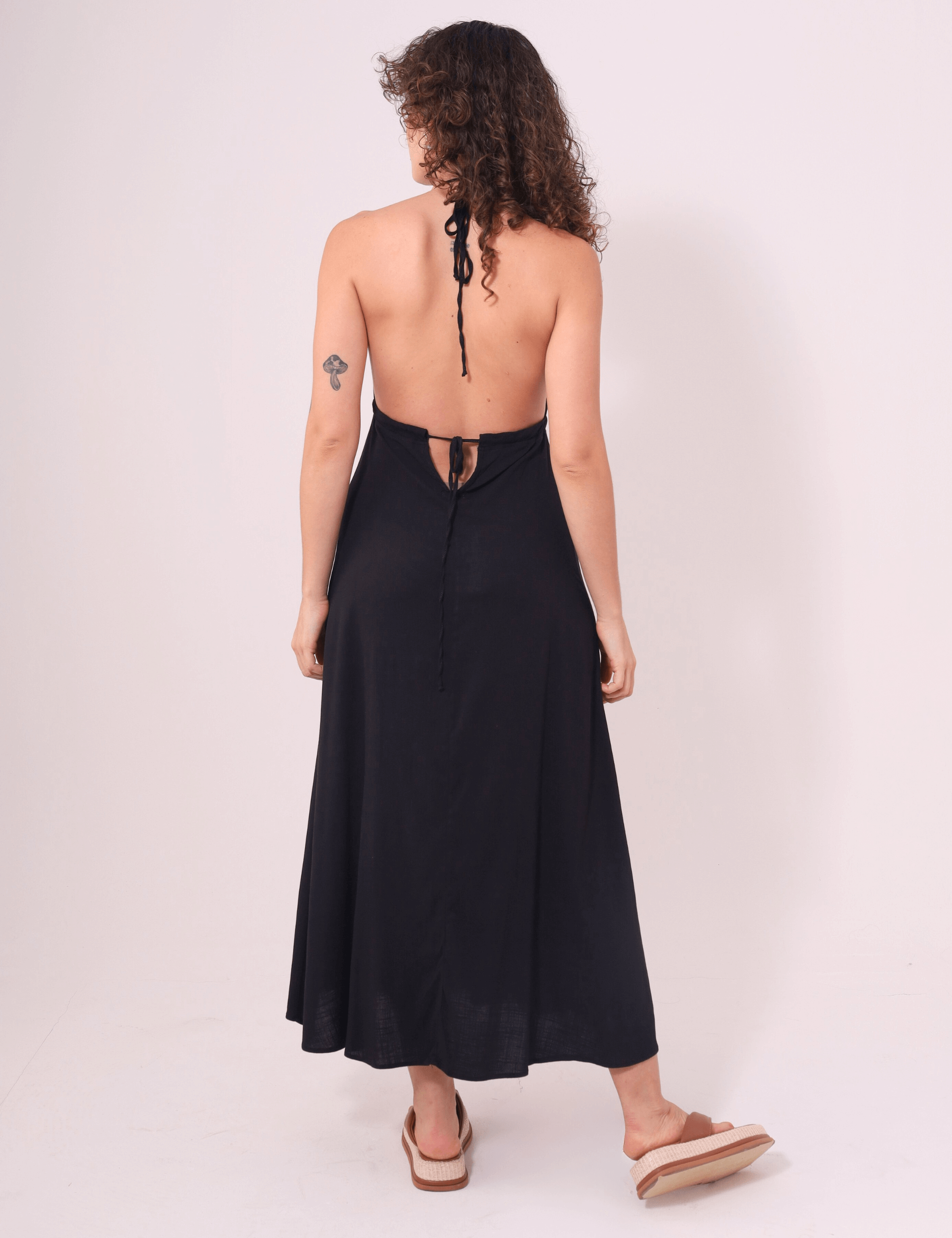 Mulher vestindo o Vestido Midi Tarsila Preto da Greenish com alças finas e costas abertas, destacando elegância e conforto.