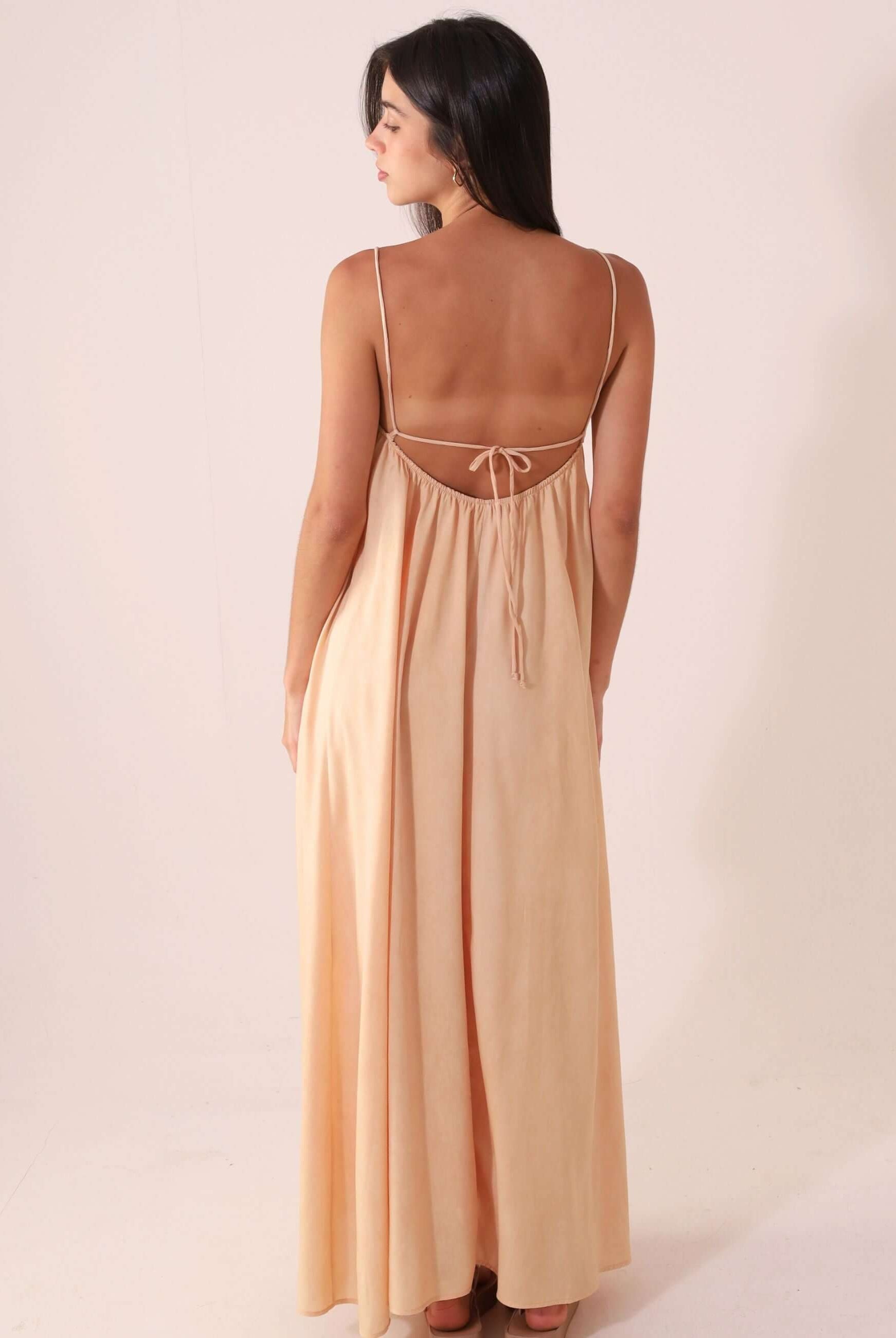 Mulher vestindo VESTIDO MIDI THÁ - BEGE da Greenish, destacando caimento suave e alças ajustáveis em cenário minimalista.