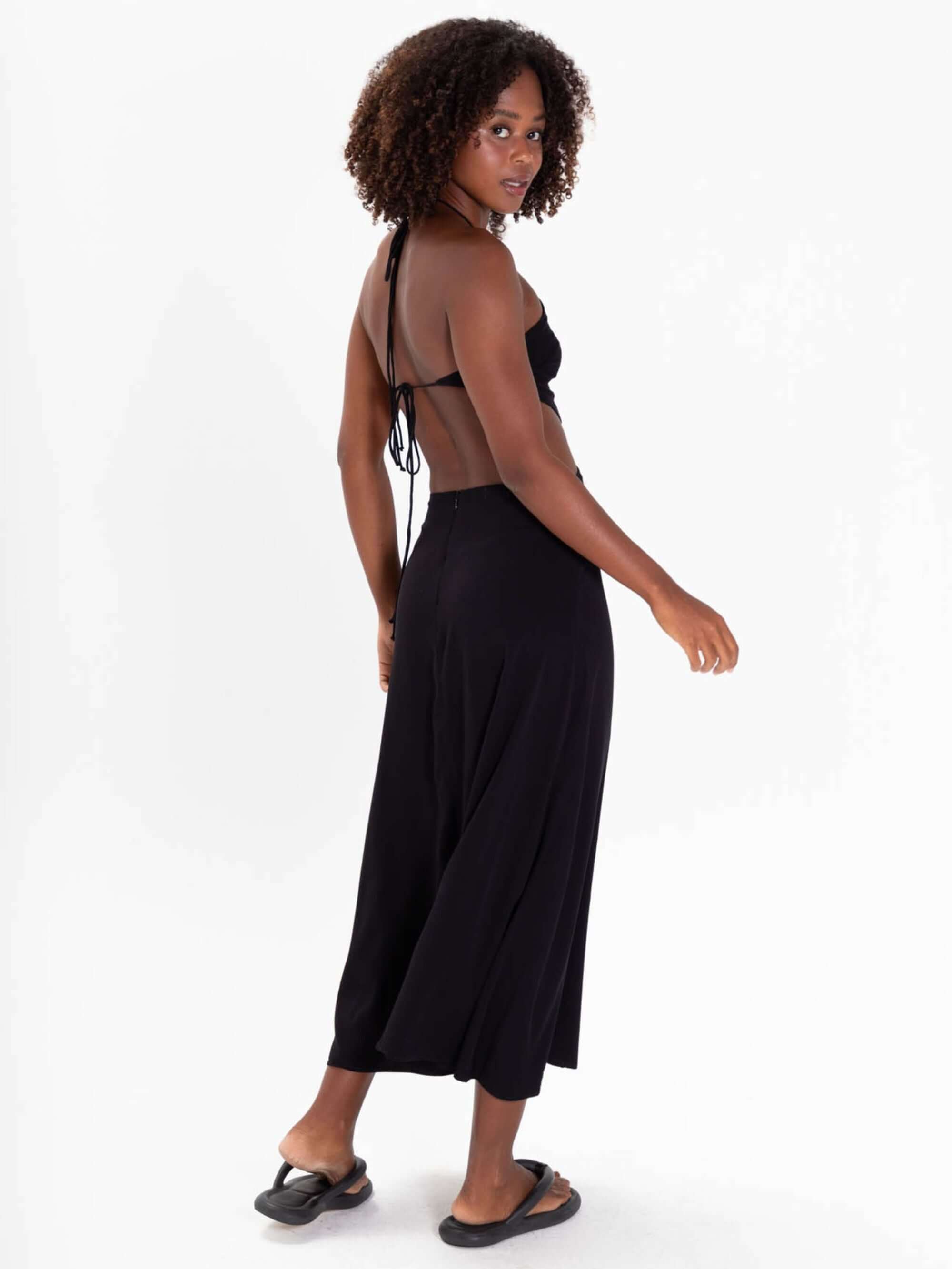 Modelo usando o Vestido Midi Yana da Greenish, preto, com detalhes de amarração e costas nuas.