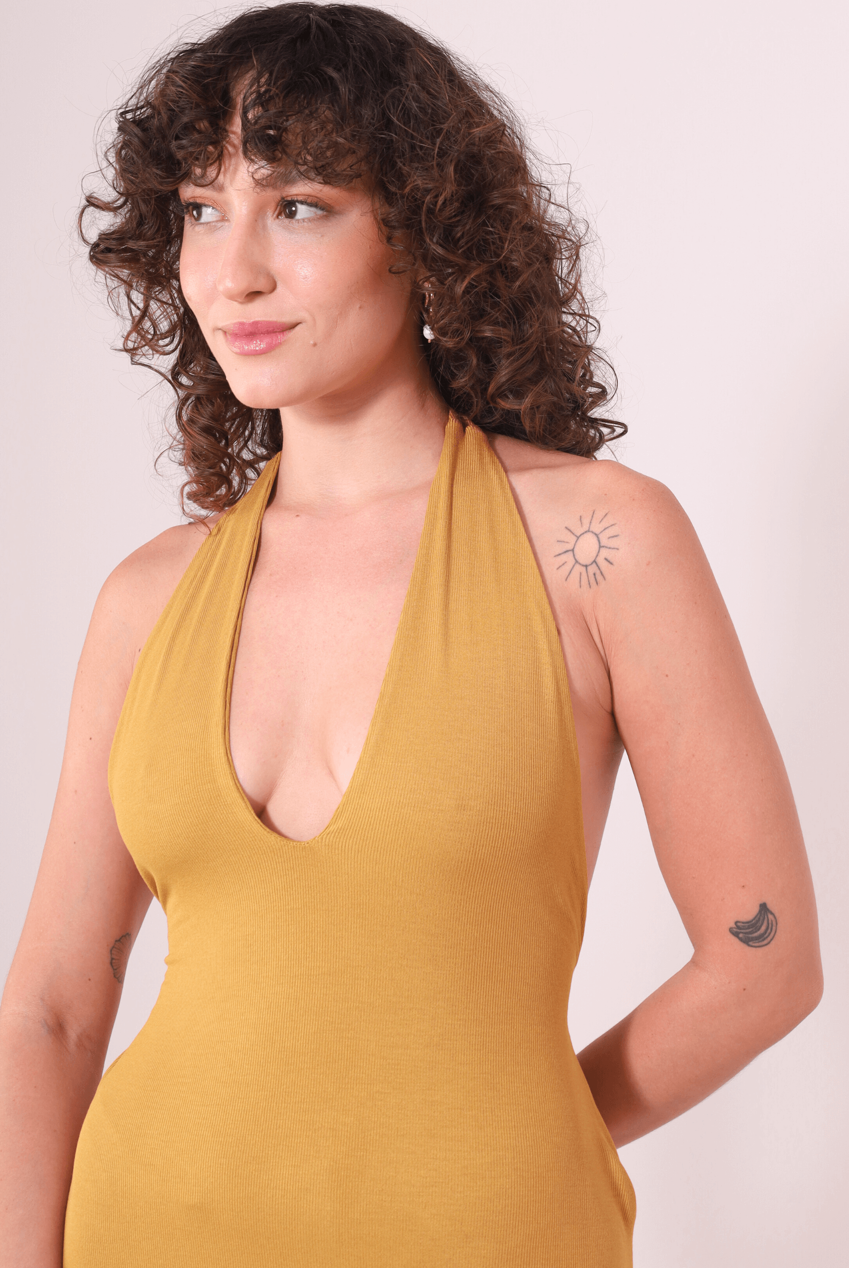 Modelo usando Vestido Longo Serena - Caqui da Greenish com decote profundo e faixas para amarração, destacando leveza e charme.