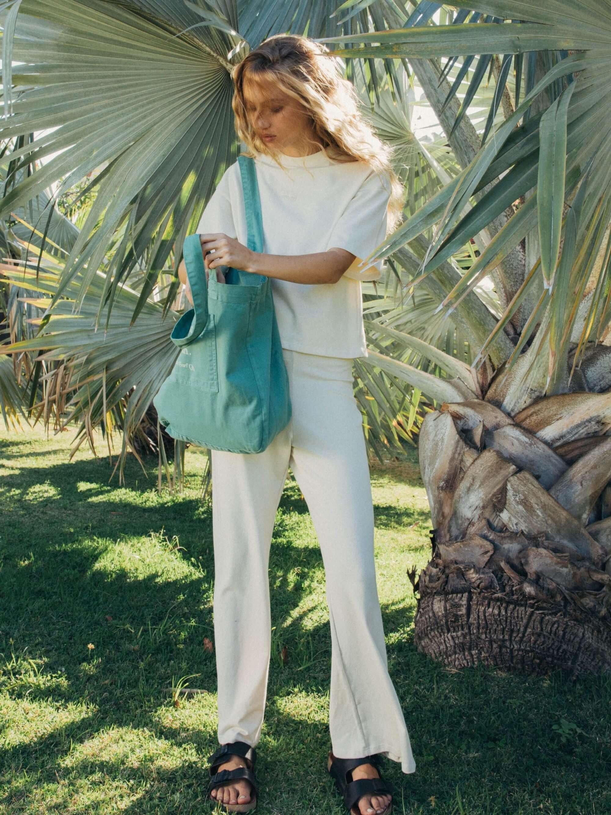 Modelo usando calça bege Gina da Greenish em meio à natureza, destacando estilo e conforto.