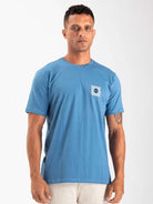 Camiseta azul Spin Chess and Sun da Greenish, modelo masculino, destacando estampa no bolso.