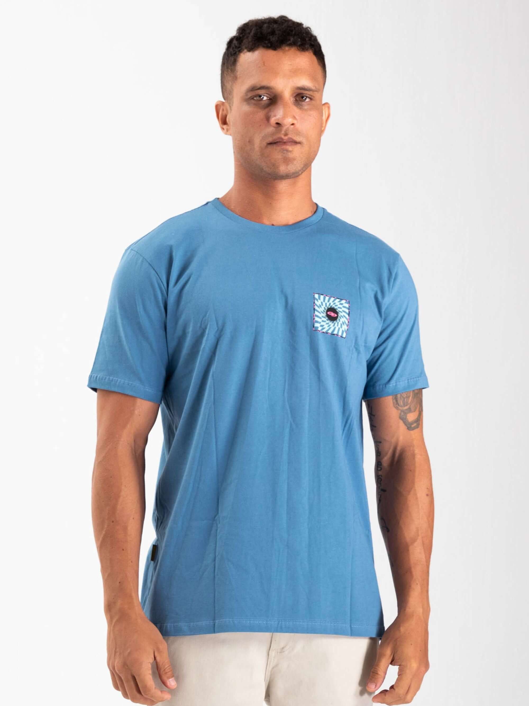 Camiseta azul Spin Chess and Sun da Greenish, modelo masculino, destacando estampa no bolso.