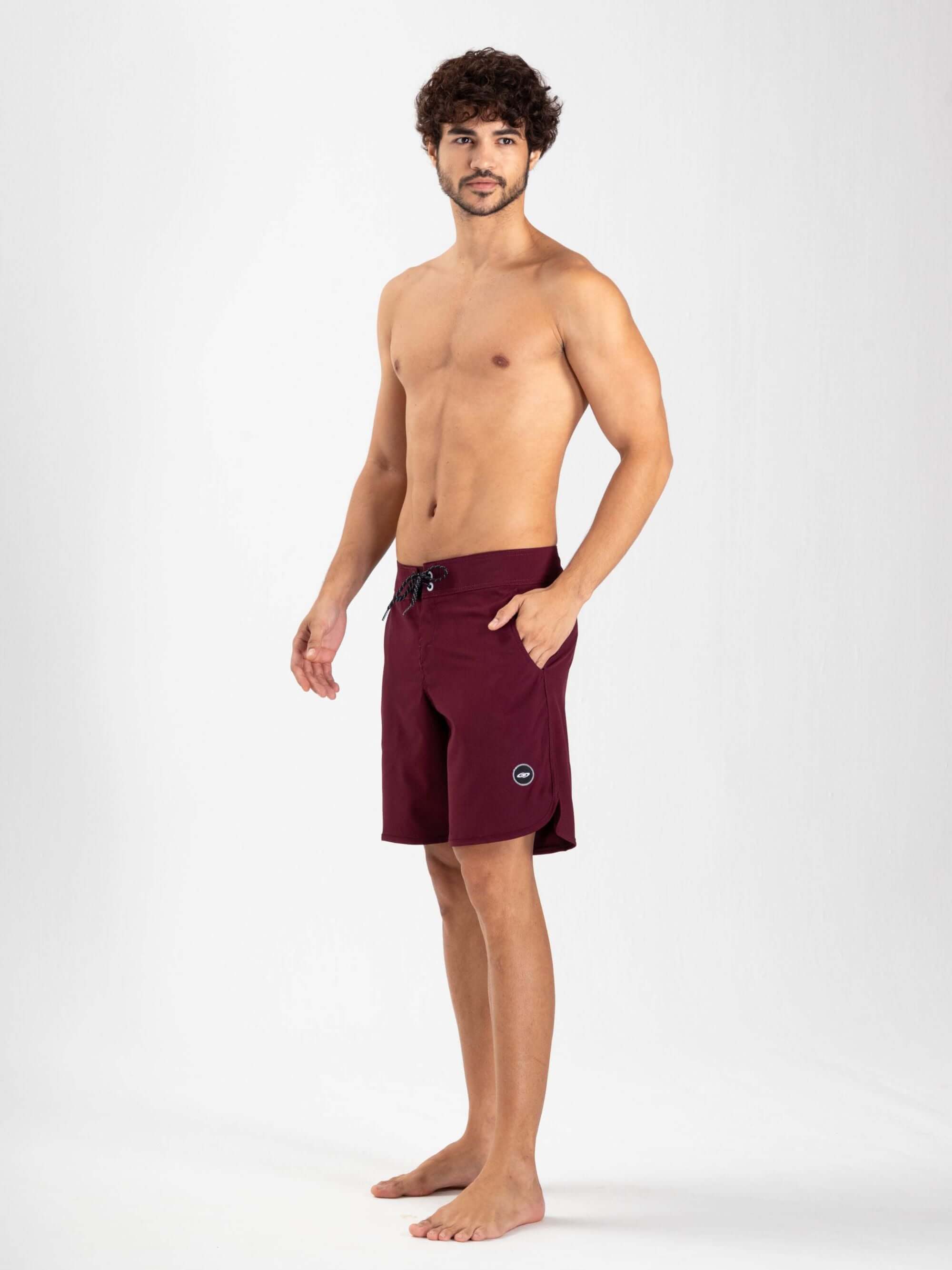 Homem usando boardshorts burgundy Boardwalk New Basic da Greenish, com cós anatômico e tecidos leves.