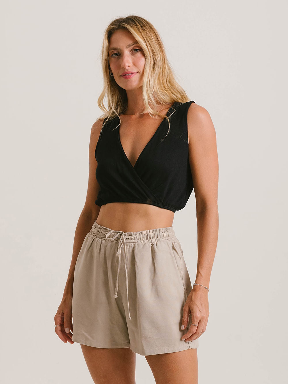 Modelo usando a Blusa Sara preta da Greenish, com caimento soltinho e decote em V.