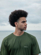 Modelo usando a camiseta verde escura Small Logo da Greenish, feita de algodão sustentável.