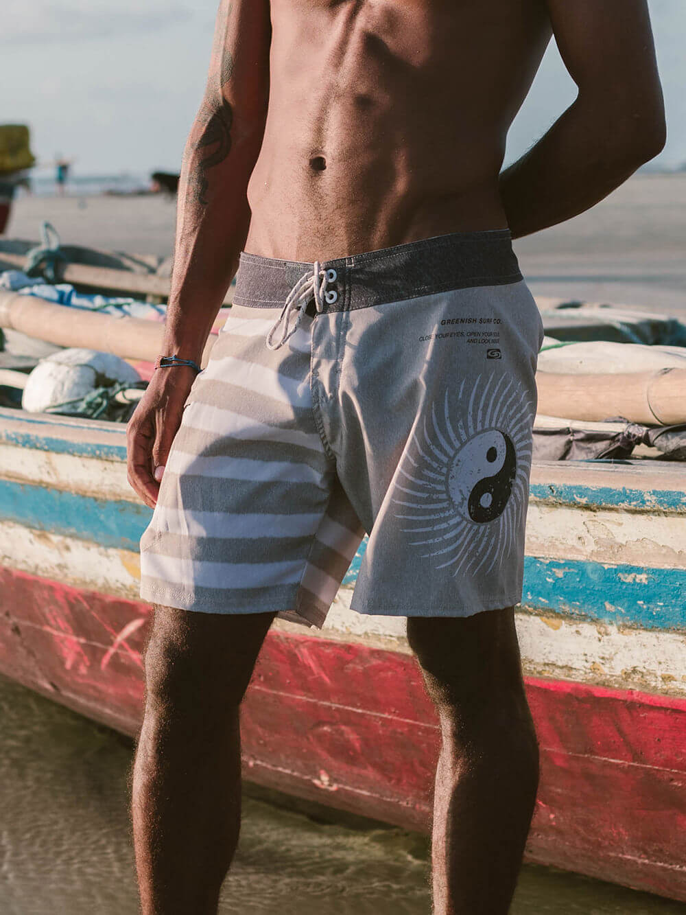 Modelo usando boardshort Yin Yang da Greenish em cáqui, ideal para conforto e estilo na praia.