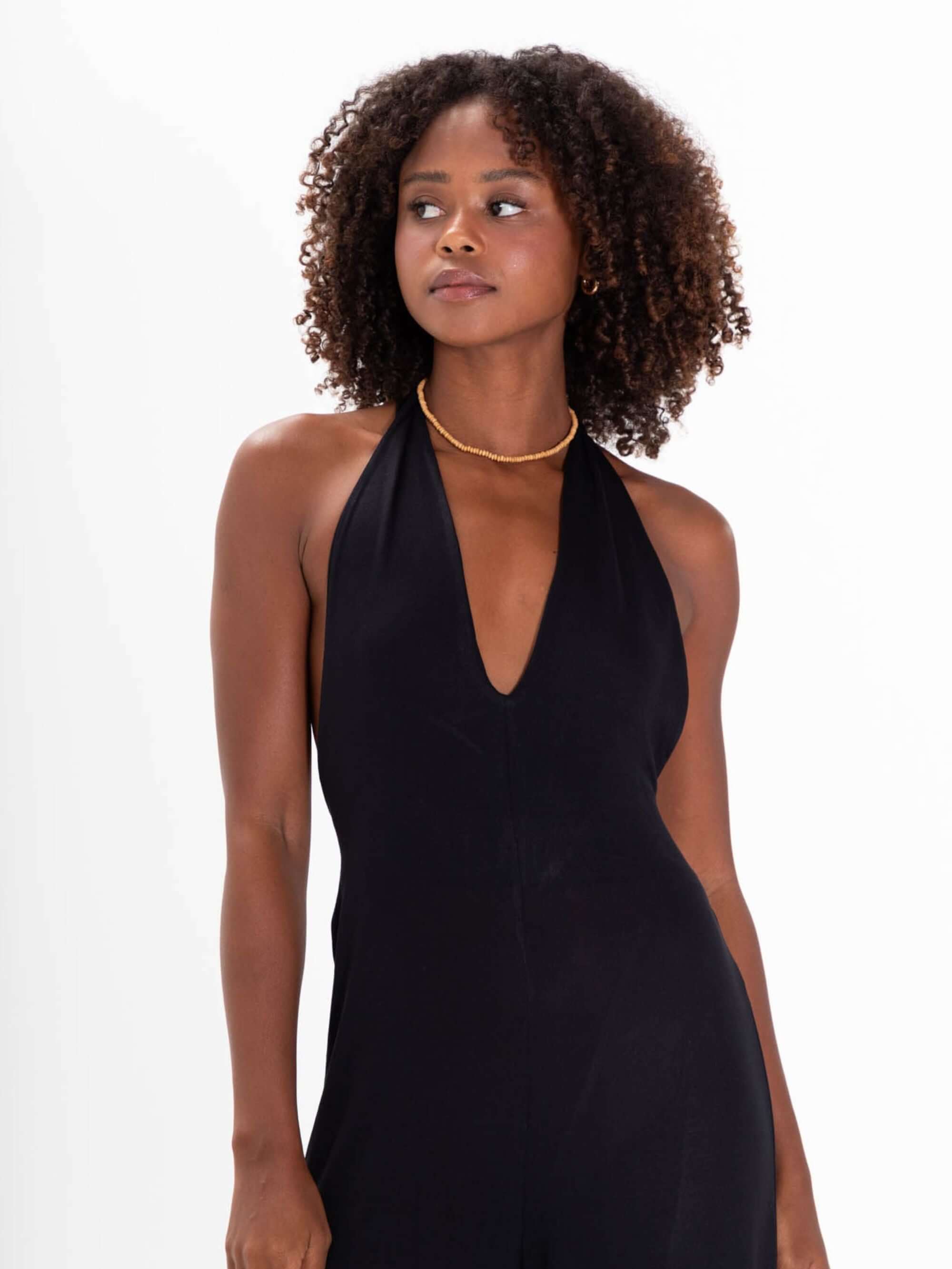 Modelo usando o Macacão Bettah Preto da Greenish, com decote em V e amarração no pescoço, destacando elegância e estilo.