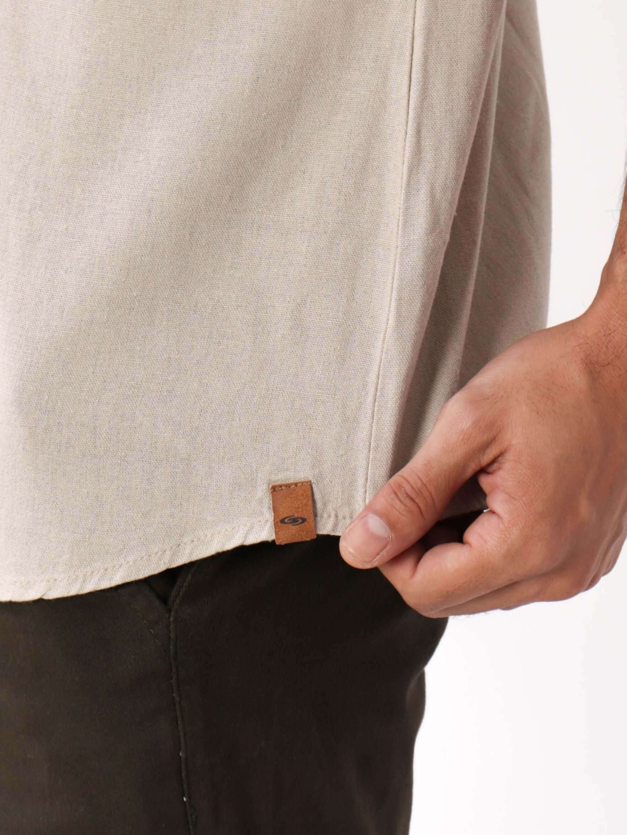 Camisa Botão Nature da Greenish em bege, com detalhe da etiqueta de couro, perfeita para sobreposições elegantes.