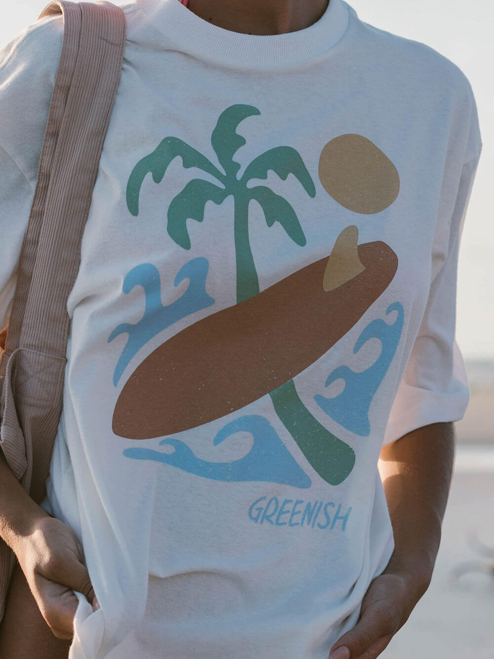 Camiseta oversized off white da Greenish com estampa tropical de surfe e palmeiras, ideal para o vibe da praia.
