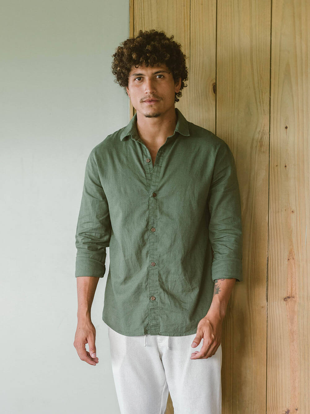 Homem usando camisa longa de linho verde da Greenish, combinando estilo casual e formal.