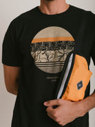 Camiseta preta Greenish com estampa tropical e bolsa laranja, ideal para um estilo casual e confortável.
