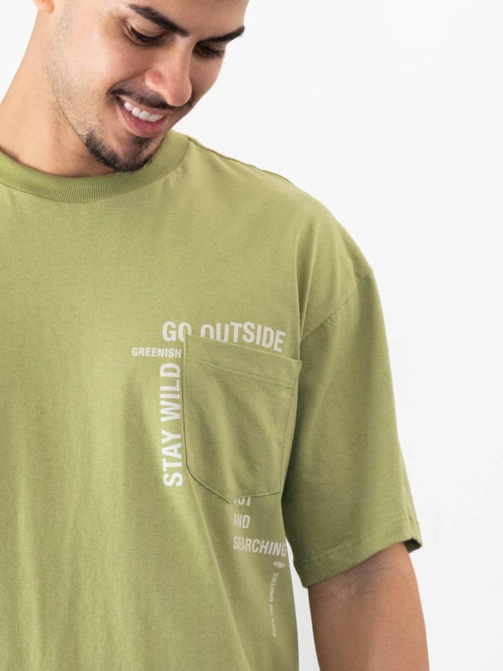 Camiseta oversized verde da marca Greenish com estampa motivacional e bolso frontal.