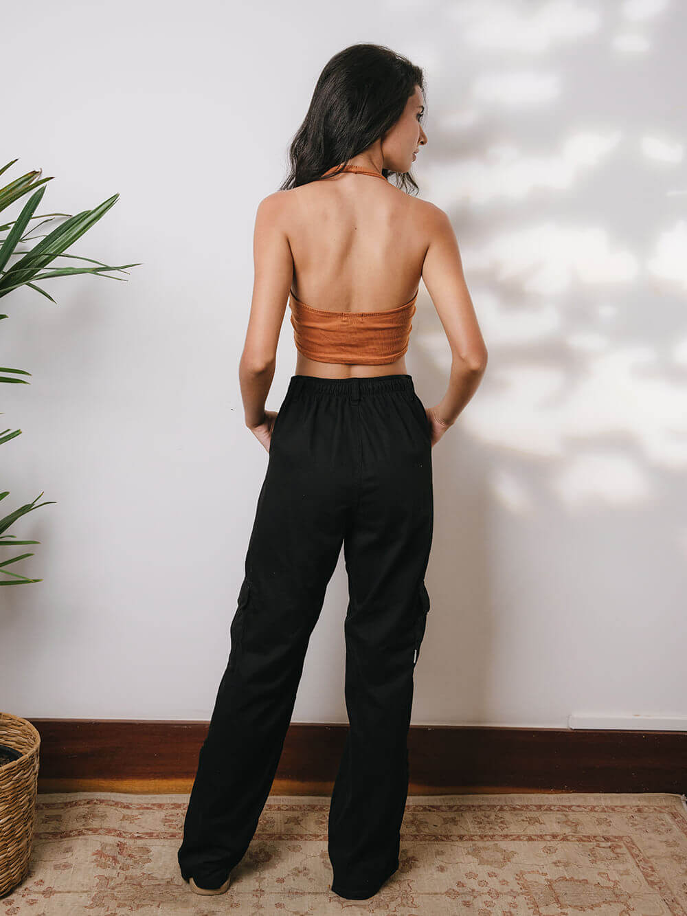 Model usando calça cargo sarja Gio preta, vista de costas, com top cropped. Estilo moderno e confortável da Greenish.