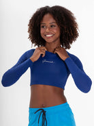 Modelo sorridente usando o Colete Cropped Basic Azul da Greenish, ideal para atividades aquáticas e proteção UV.