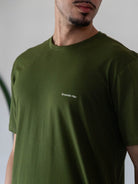 Camiseta verde escuro Greenish com logo pequeno, feita de algodão sustentável, estilo minimalista e clássico.