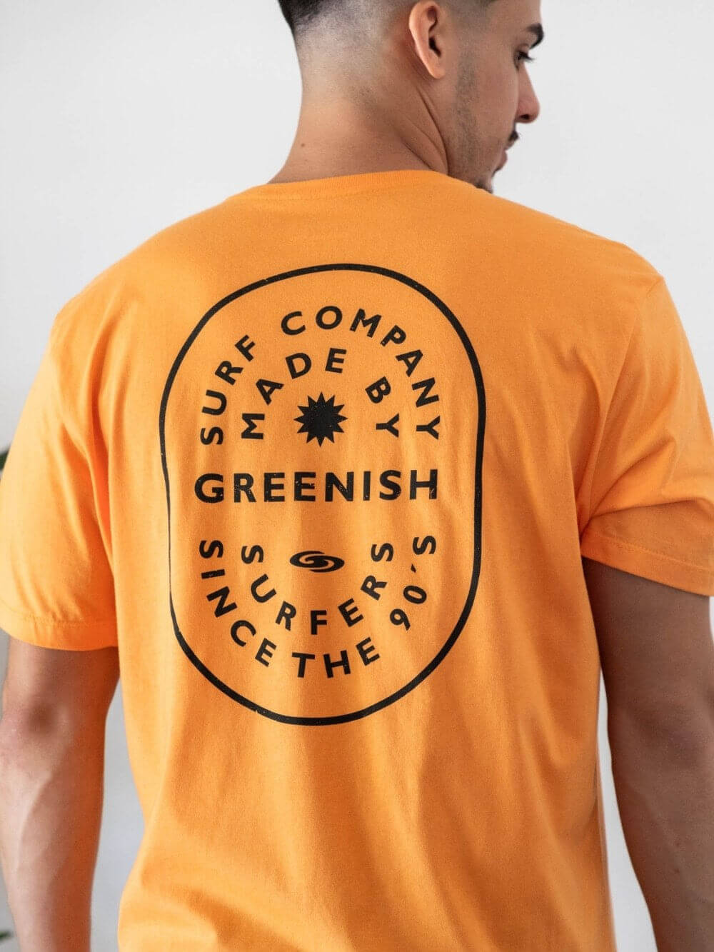 Camiseta laranja da Greenish com estampa Surf Company, autenticidade e conforto para surfistas desde os anos 90.
