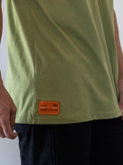 Camiseta oversized verde da marca Greenish, destacando o detalhe da etiqueta na lateral.