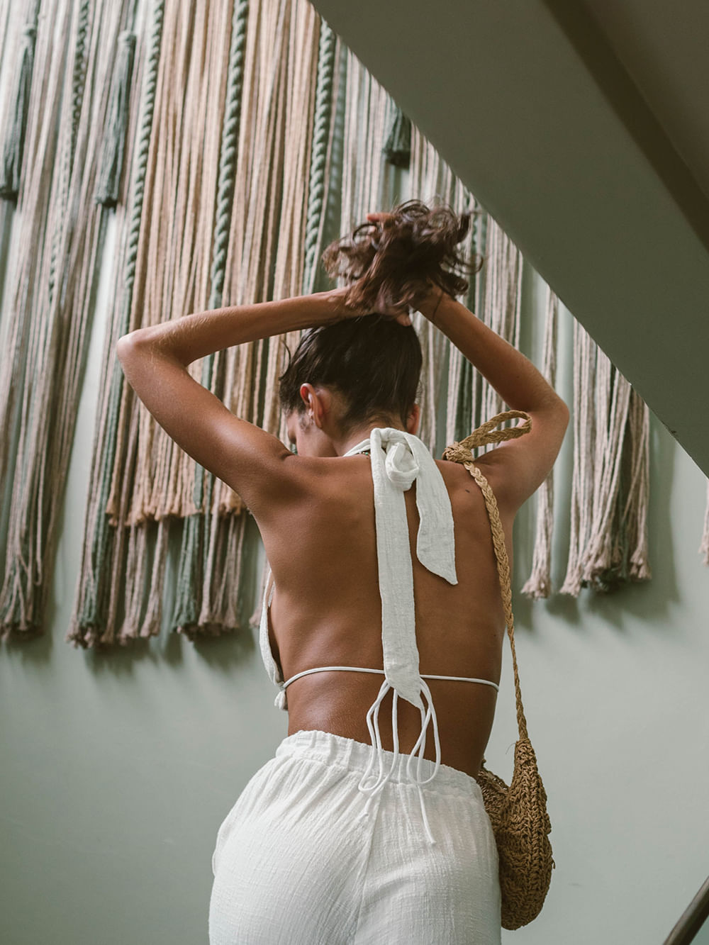 Top cropped branco da Greenish, mostrando detalhes das costas e amarração, com fundo estiloso de cordas.