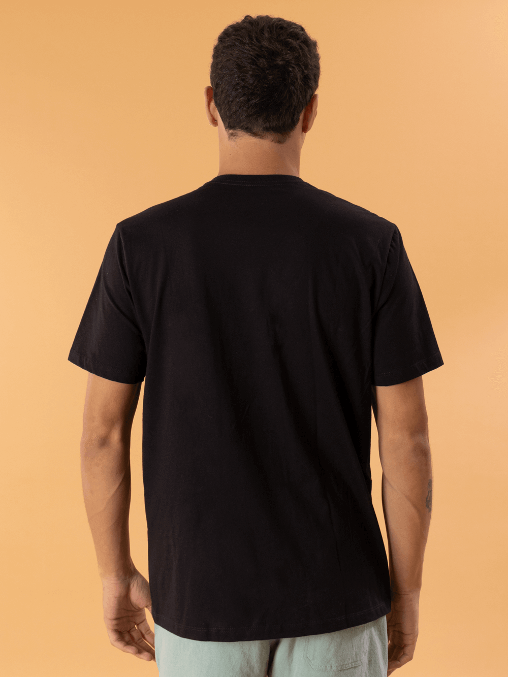 Camiseta preta masculina da Greenish, mostrando vista traseira em fundo laranja. Conforto e estilo para o dia a dia.