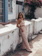 Mulher em calça Cecília bege da Greenish, com estilo e conforto, relaxando em ambiente urbano e ensolarado.