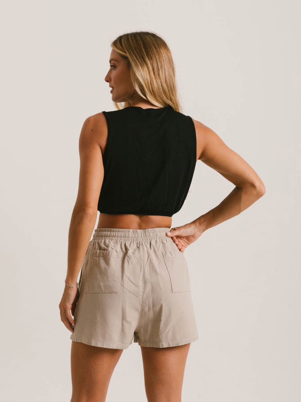 Modelo usando blusa cropped preta da Greenish, exibindo o caimento solto e shorts confortáveis.