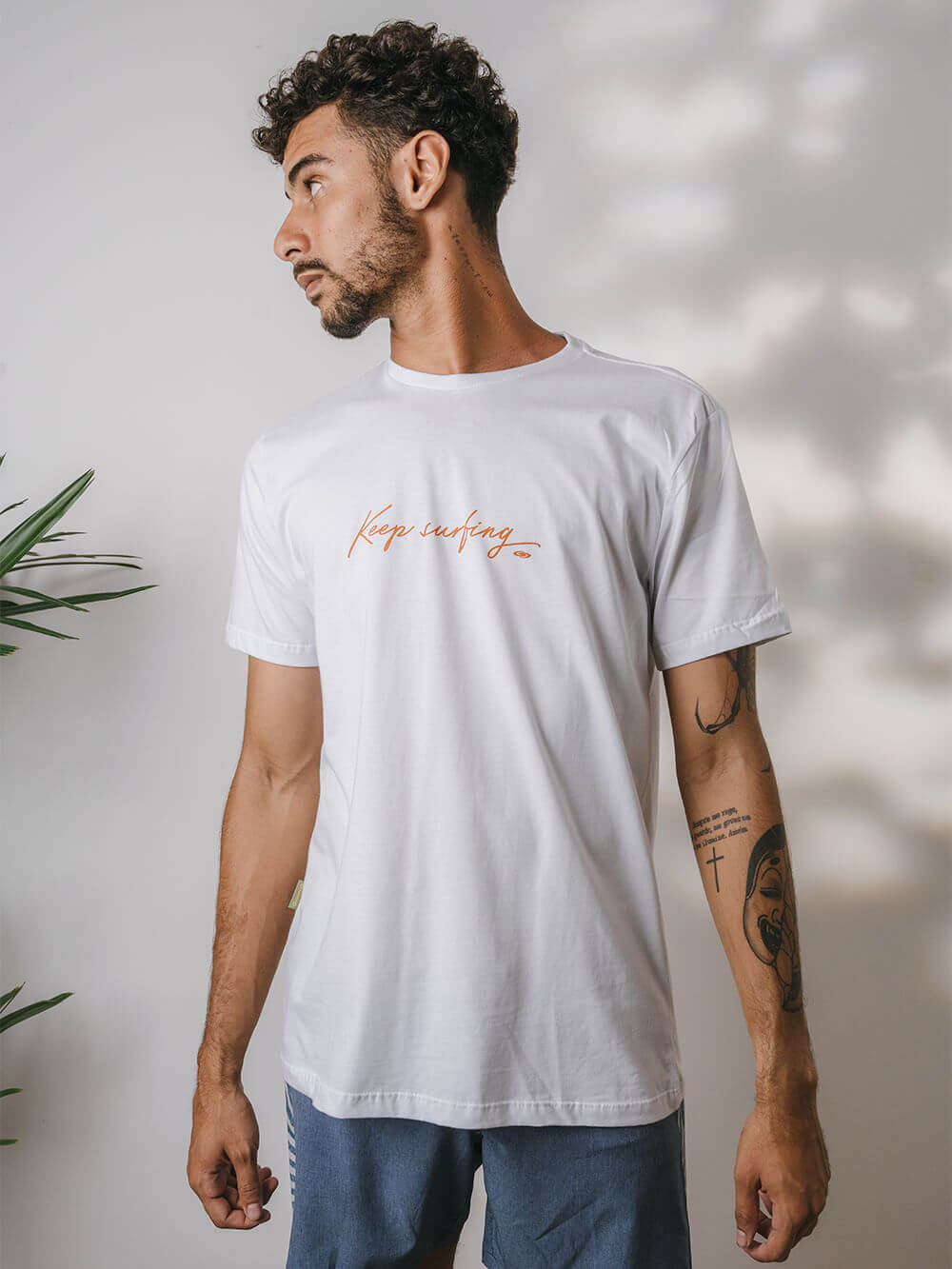 Camiseta branca da Greenish com estampa minimalista 'Keep Surfing' em um modelo masculino moderno.