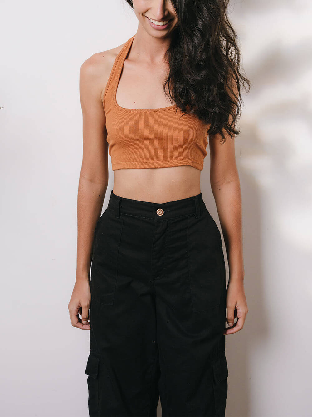 Modelo usando calça cargo sarja preta da Greenish com blusa cropped laranja, estampa casual e moderna.