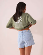 Greenish SHORT JEANS DAYANA - AZUL com cintura alta e lavagem vintage, usado por mulher de costas em ambiente casual.