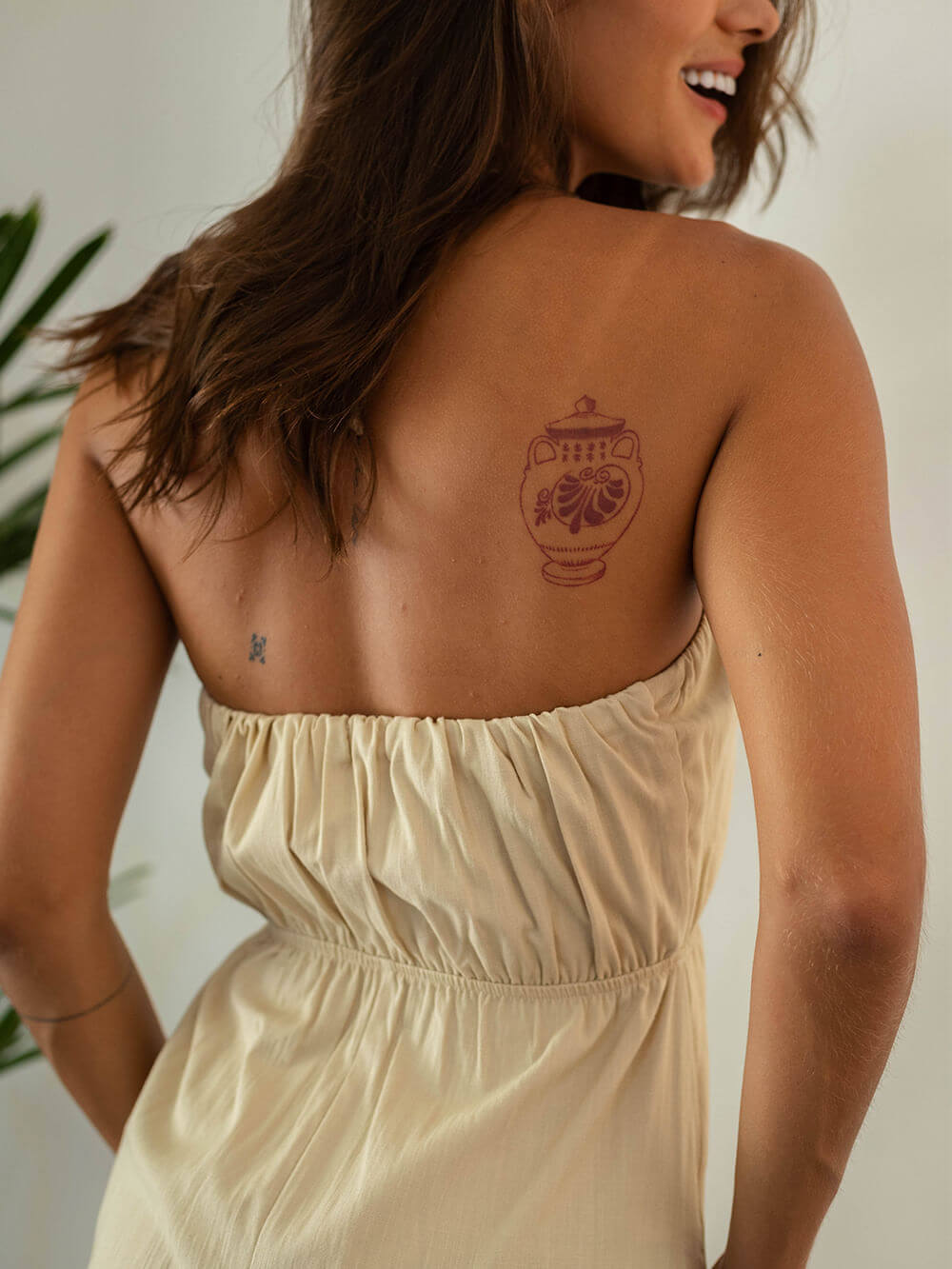 Modelo usando vestido curto bege, com um lindo desenho no ombro, exalando estilo e conforto.