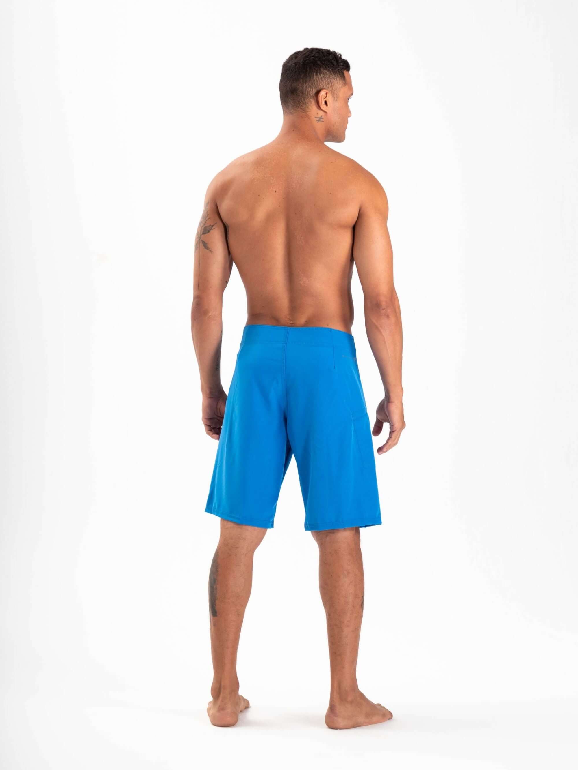 Man wearing Greenish Total Stretch boardshorts in azul, designed for high-performance activities and quick drying.