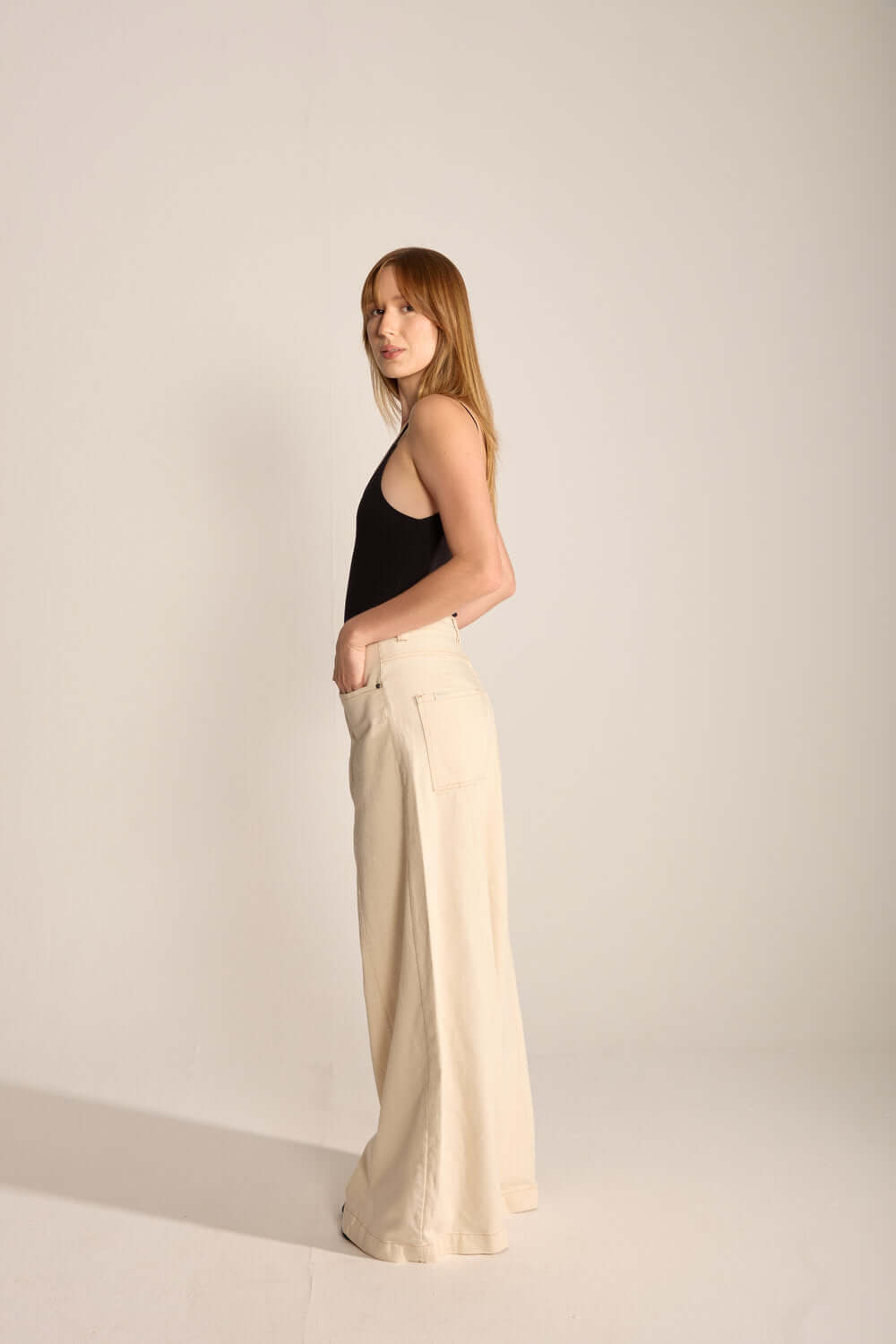 Modelo stylish vestindo calça de alfaiataria clara e blusa preta, destacando elegância e estilo minimalista.
