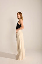 Modelo stylish vestindo calça de alfaiataria clara e blusa preta, destacando elegância e estilo minimalista.