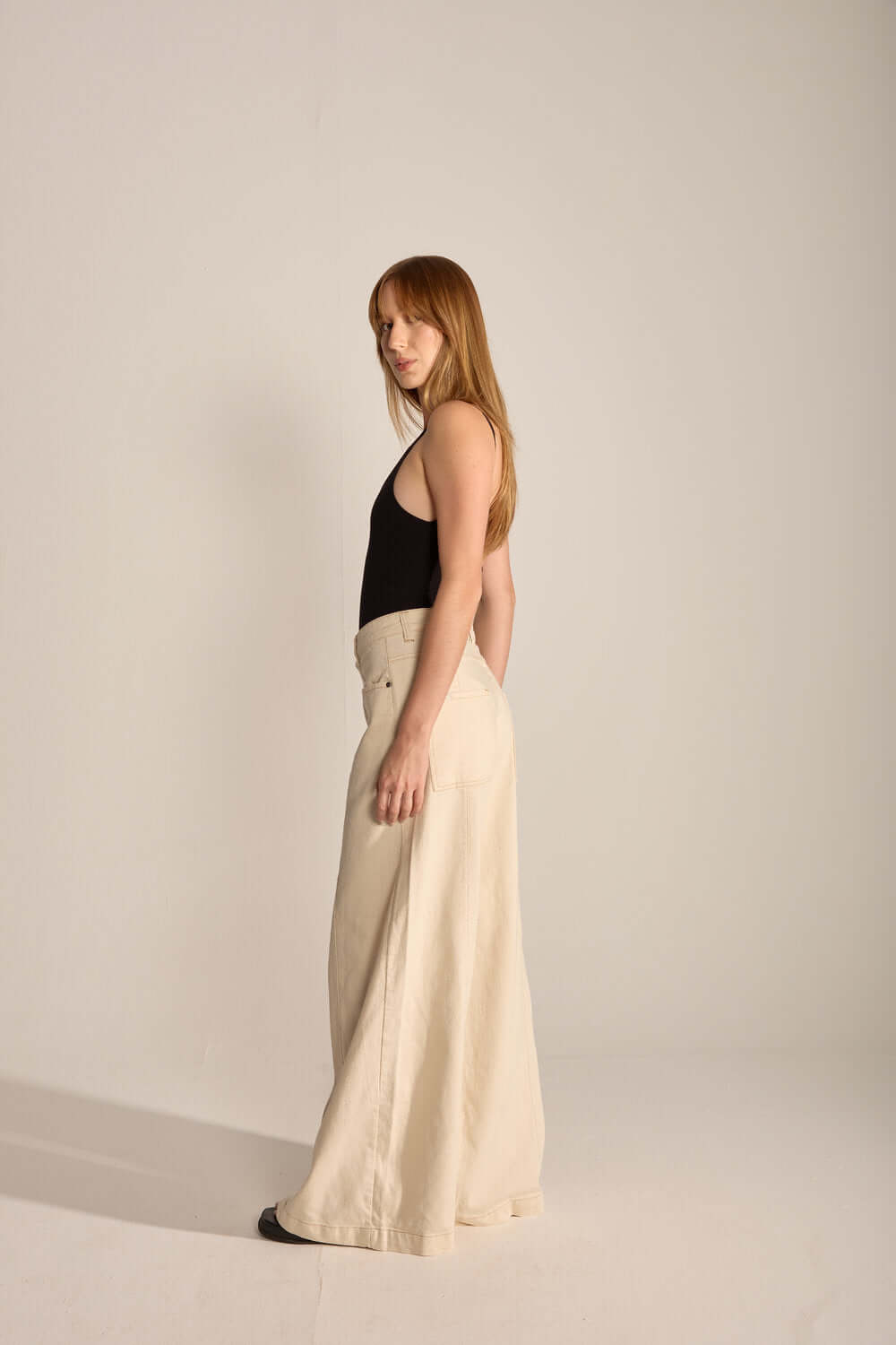 Modelo usando body Célia preto e calça larga em tom claro, exibe look minimalista e elegante da marca Greenish.
