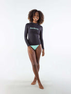 Modelo usando camiseta de surf preta com estampa Cumbuco e biquíni verde, da marca Greenish.