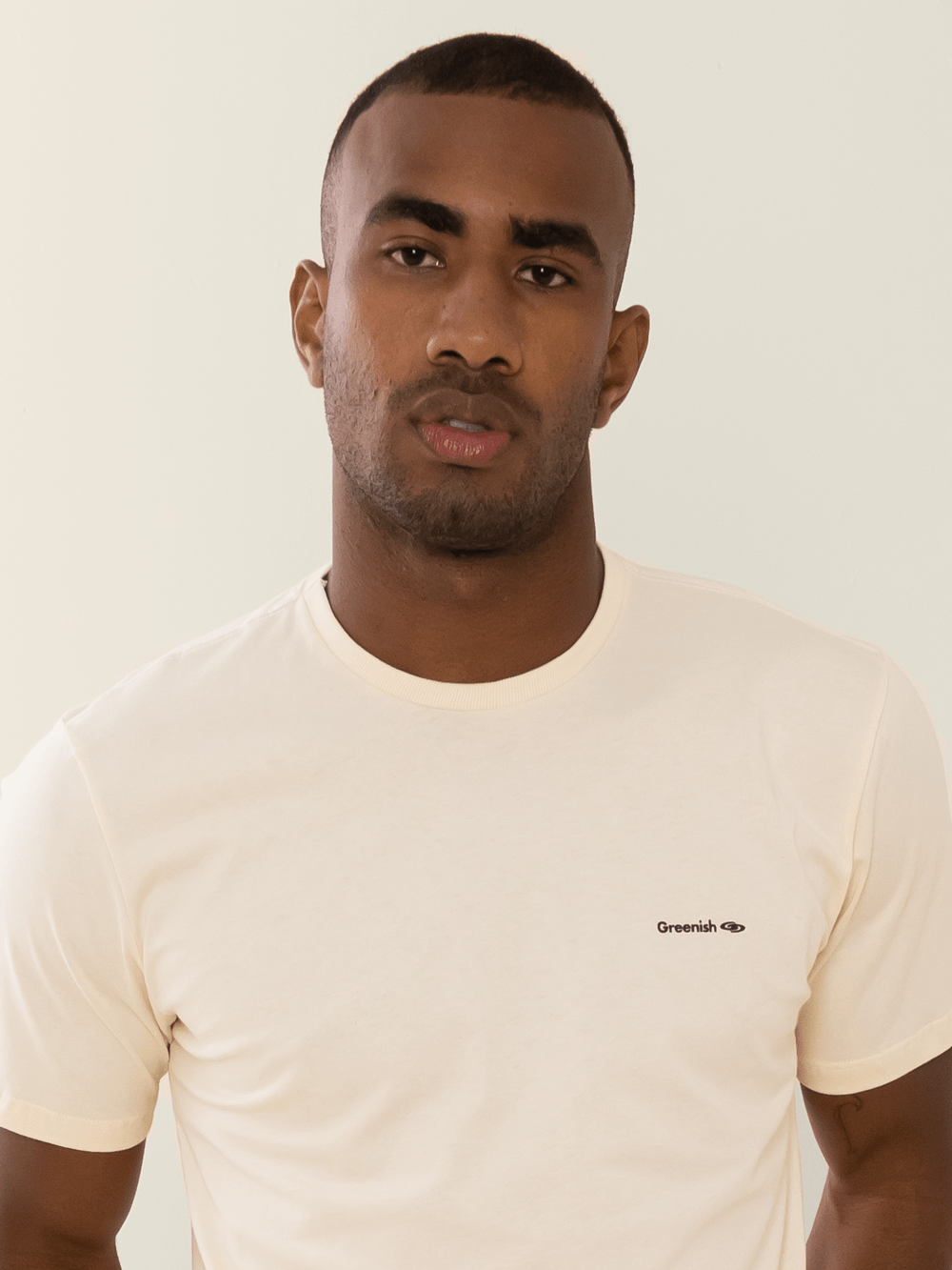 Camiseta bege minimalista com logo Greenish em malha 100% algodão sustentável.