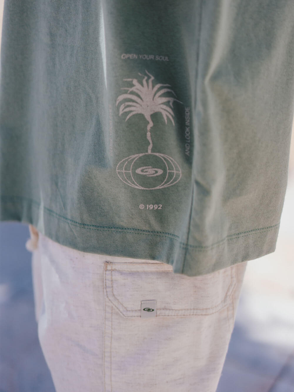 Camiseta oversized verde da Greenish com estampa de palmeira e logo, estilo moderno e confortável.