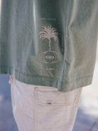 Camiseta oversized verde da Greenish com estampa de palmeira e logo, estilo moderno e confortável.